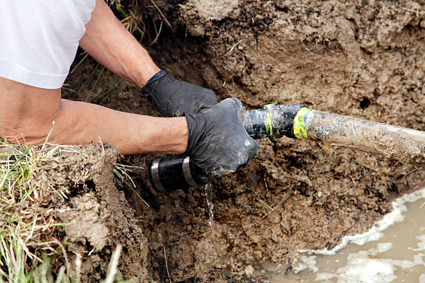 Plumber Repairing a Broken Pipe in a Septic Field